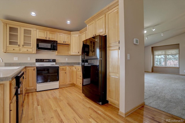 kitchen featuring sink, rail lighting, lofted ceiling, black appliances, and light wood-type flooring