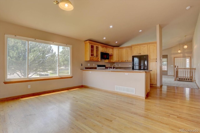 kitchen featuring light brown cabinets, lofted ceiling, black appliances, light wood-type flooring, and kitchen peninsula