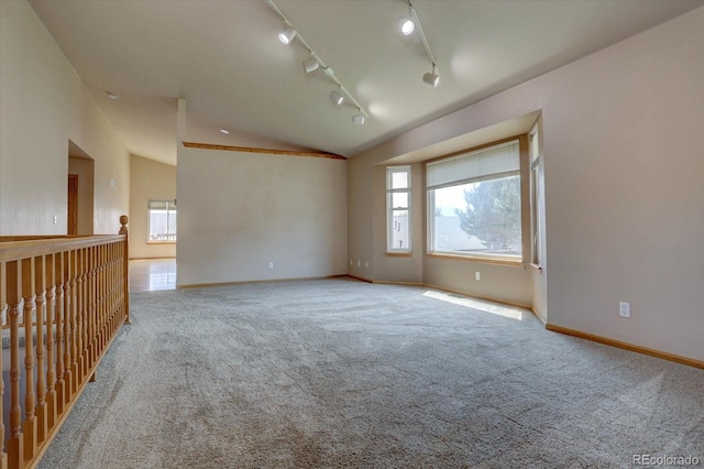 spare room featuring light carpet, track lighting, and vaulted ceiling