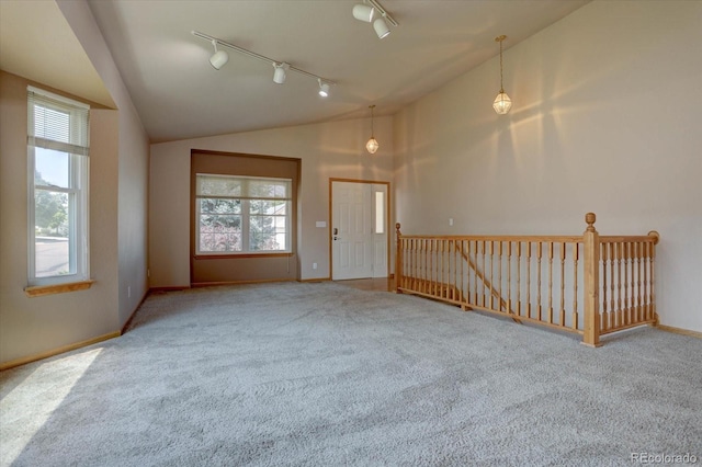 carpeted spare room with rail lighting, a wealth of natural light, and lofted ceiling