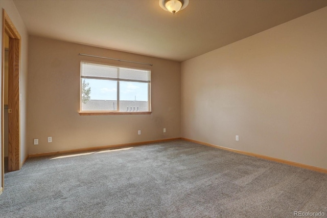 carpeted empty room featuring baseboards