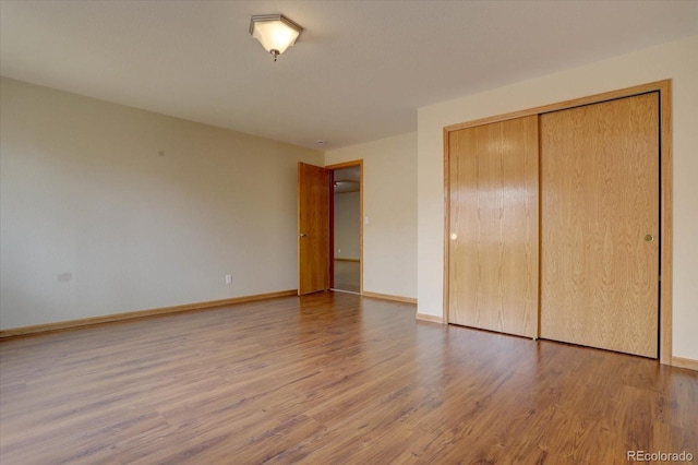 unfurnished bedroom featuring a closet, baseboards, and wood finished floors