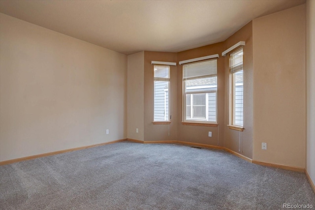 empty room featuring carpet flooring, visible vents, and baseboards