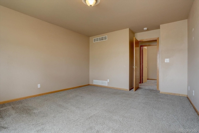 empty room featuring carpet, visible vents, and baseboards