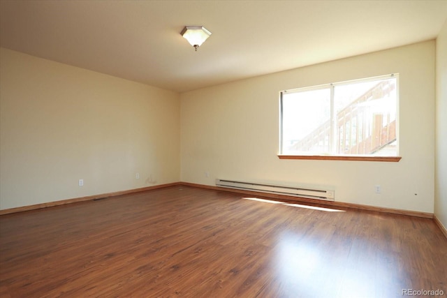 spare room with a baseboard radiator, visible vents, baseboards, and wood finished floors