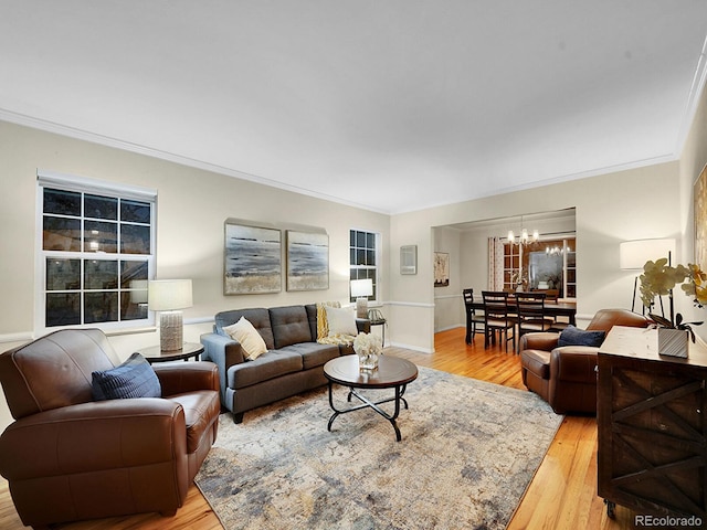 living room with ornamental molding, light wood-type flooring, and a chandelier