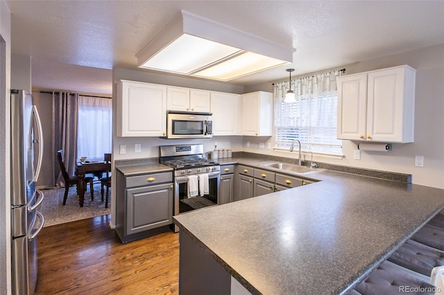 kitchen featuring stainless steel appliances, kitchen peninsula, sink, and white cabinets