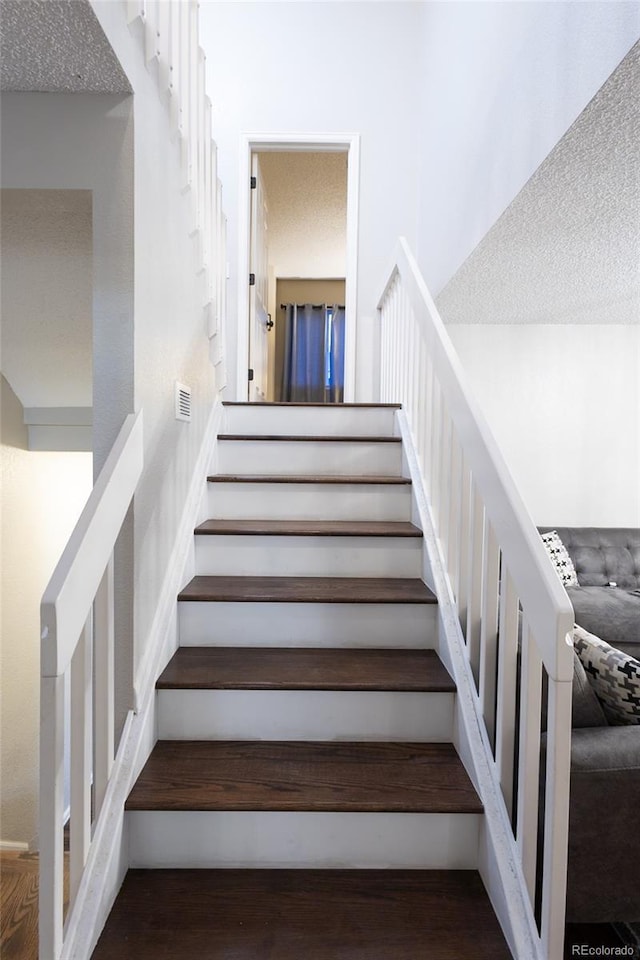 stairs with wood-type flooring and a textured ceiling