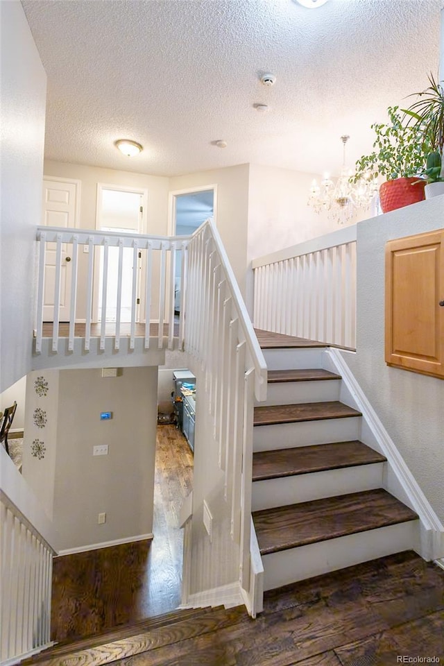 staircase featuring wood-type flooring and a textured ceiling