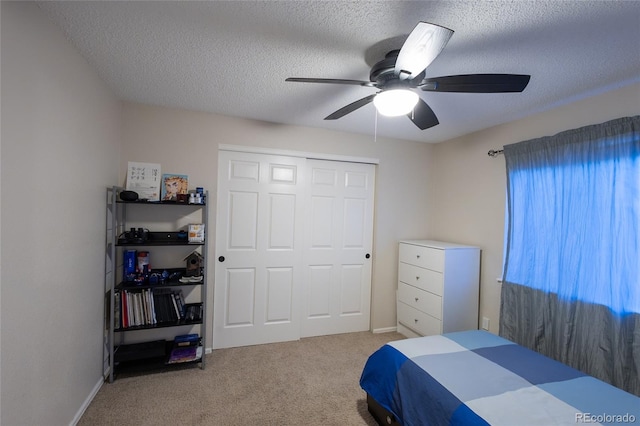 carpeted bedroom featuring ceiling fan, a closet, and a textured ceiling