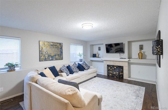 living room with dark hardwood / wood-style flooring, a tile fireplace, and a textured ceiling