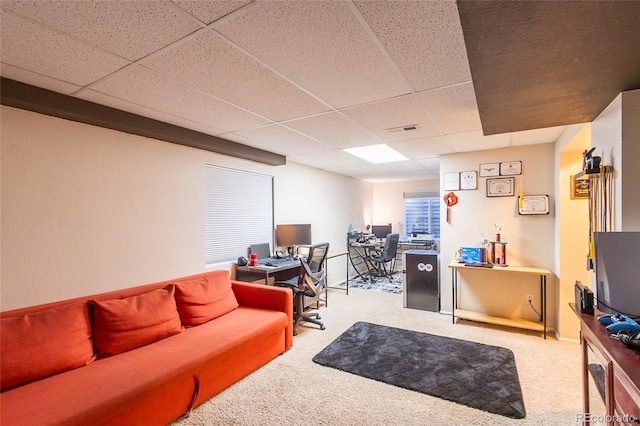 living room with a paneled ceiling and light colored carpet