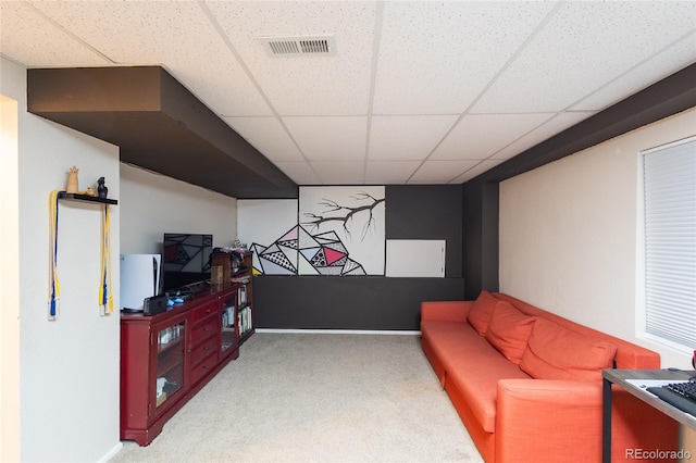 living area featuring light carpet and a paneled ceiling