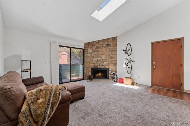 living area featuring vaulted ceiling with skylight, a fireplace, and carpet flooring