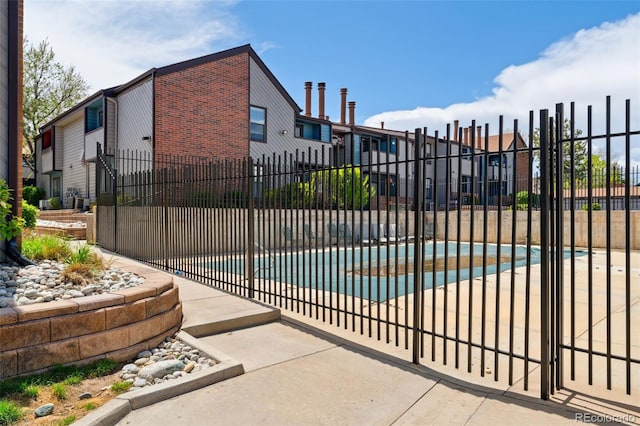 view of gate with fence, a residential view, and a fenced in pool