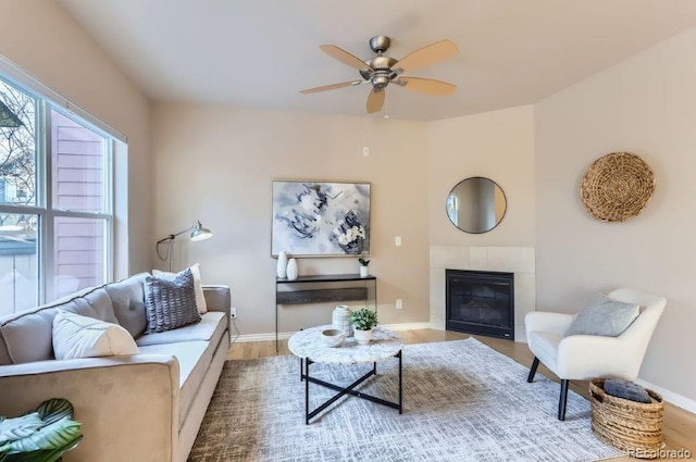 living room with ceiling fan, a tile fireplace, and hardwood / wood-style floors