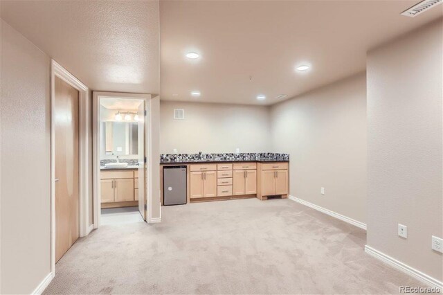 kitchen with dishwasher, light brown cabinetry, light colored carpet, and sink