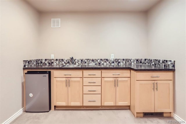 kitchen featuring sink, tasteful backsplash, light brown cabinetry, and stainless steel fridge