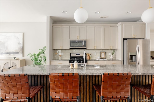 kitchen featuring a breakfast bar, light stone counters, and stainless steel appliances