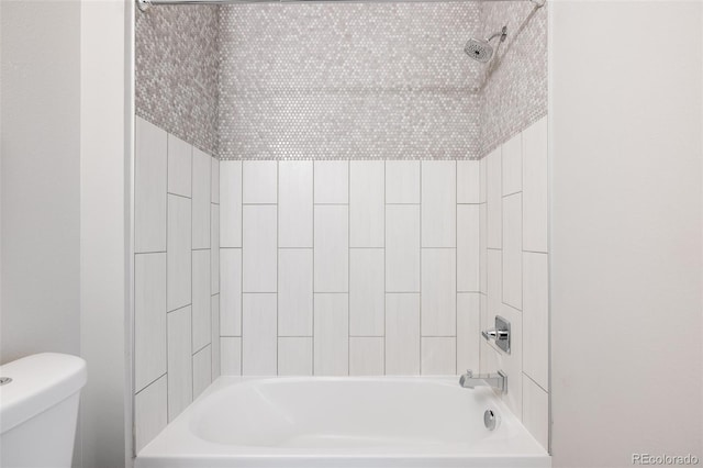 bathroom featuring tiled shower / bath combo and toilet