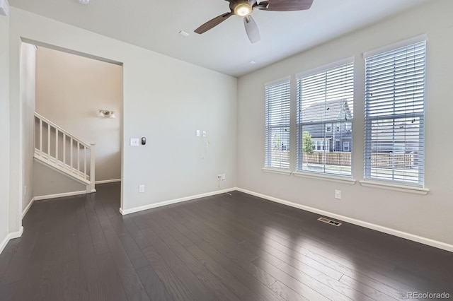 unfurnished room with dark wood-style flooring, visible vents, baseboards, and ceiling fan