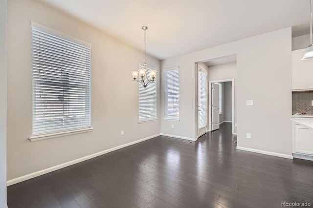 unfurnished dining area with baseboards, dark wood-style flooring, and a chandelier