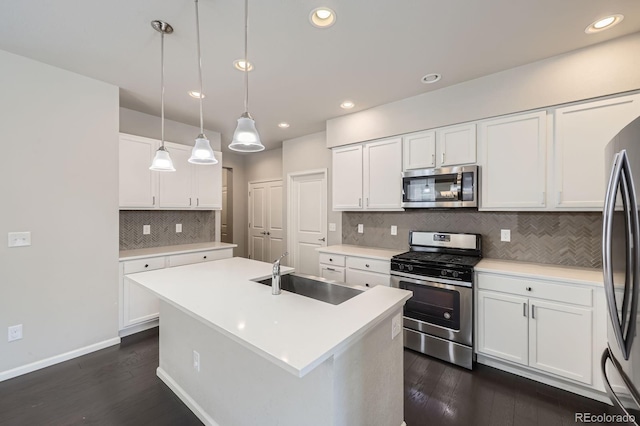 kitchen with white cabinets, dark wood finished floors, stainless steel appliances, a sink, and decorative backsplash