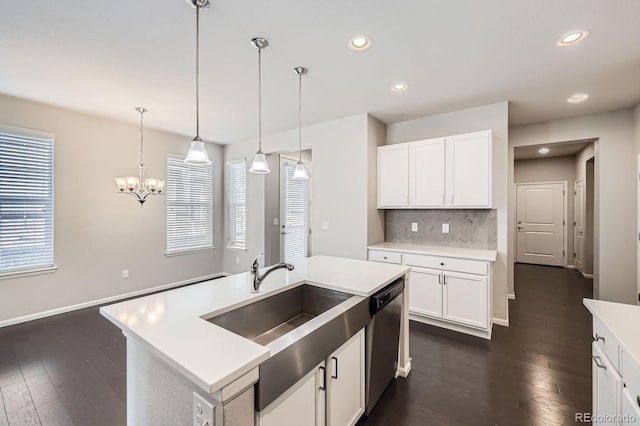 kitchen with dark wood-style floors, light countertops, stainless steel dishwasher, pendant lighting, and tasteful backsplash