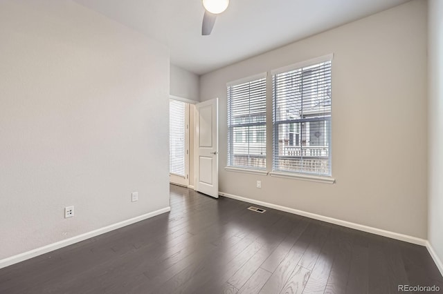 spare room with baseboards, a ceiling fan, and dark wood-style floors