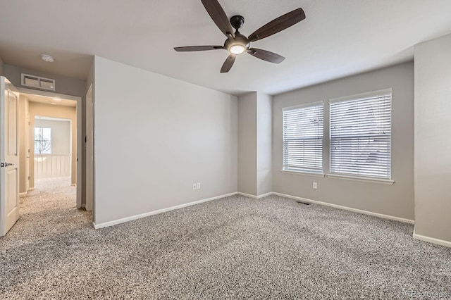 carpeted empty room with visible vents, baseboards, and ceiling fan