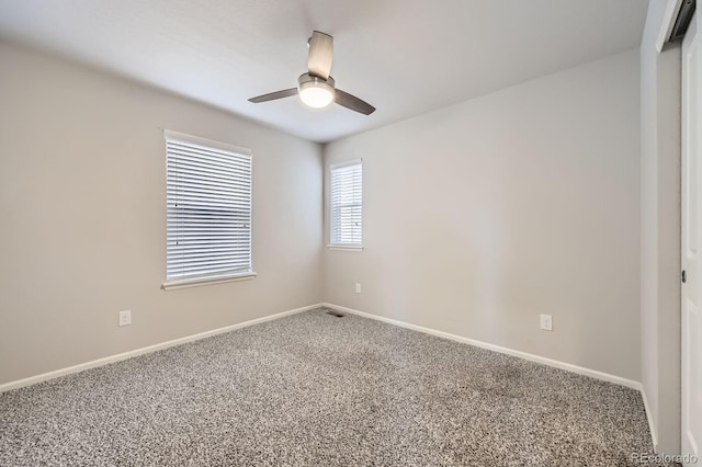 spare room with carpet floors, visible vents, a ceiling fan, and baseboards