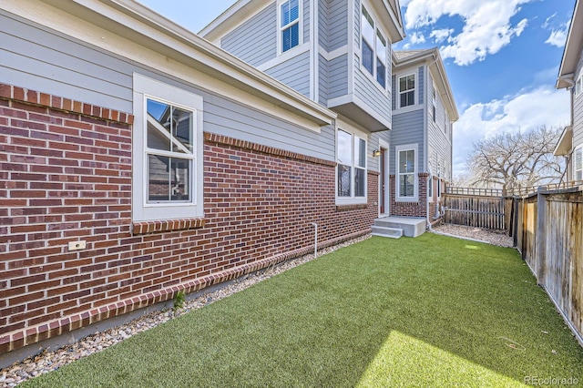 view of home's exterior featuring a lawn, a fenced backyard, and brick siding