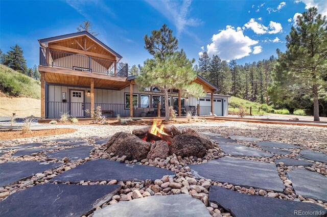 2230 S Platte River Rd, Sedalia, CO 80135 - view of front of house featuring a garage, board and batten siding, an outdoor fire pit, and a balcony