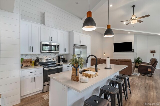 2230 S Platte River Rd, Sedalia, CO 80135 - kitchen with appliances with stainless steel finishes, a sink, a breakfast bar area, wood finished floors, and tasteful backsplash