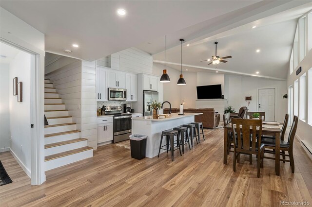 2230 S Platte River Rd, Sedalia, CO 80135 - kitchen featuring light wood-style floors, open floor plan, a kitchen breakfast bar, a ceiling fan, and appliances with stainless steel finishes