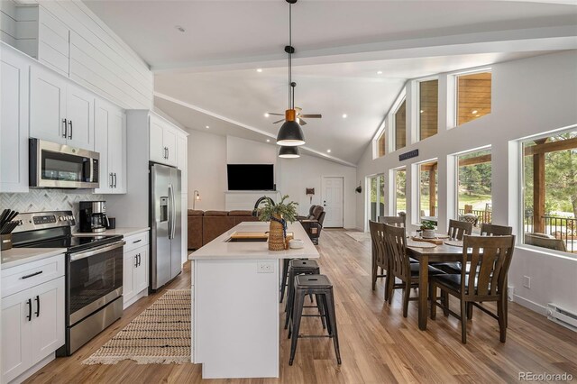 2230 S Platte River Rd, Sedalia, CO 80135 - kitchen featuring backsplash, stainless steel appliances, light wood finished floors, and open floor plan