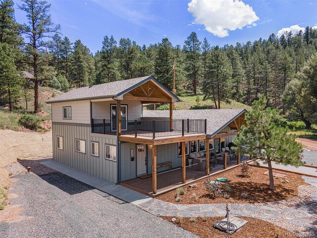 2230 S Platte River Rd, Sedalia, CO 80135 - view of front of home with a shingled roof, a view of trees, and board and batten siding