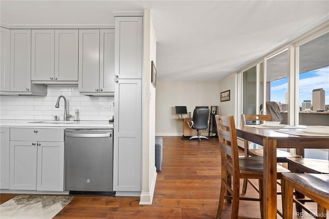 kitchen with decorative backsplash, dark wood finished floors, dishwasher, gray cabinetry, and a sink