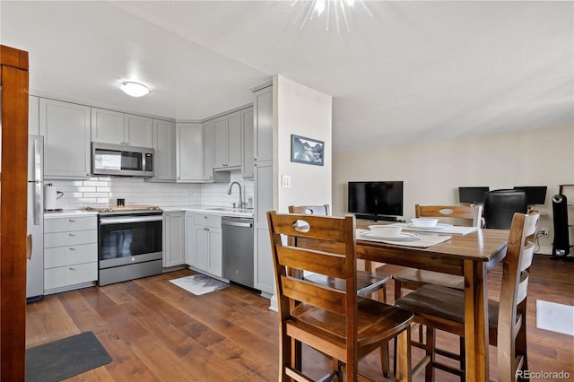 kitchen featuring gray cabinetry, stainless steel appliances, a sink, light countertops, and backsplash