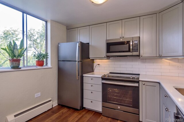 1085 N Lafayette St Unit 704, Denver, CO 80218 - kitchen featuring appliances with stainless steel finishes, a baseboard radiator, gray cabinets, decorative backsplash, and light countertops