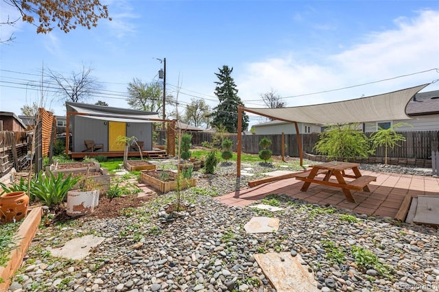 fenced backyard featuring a vegetable garden, an outbuilding, a patio, and a storage unit