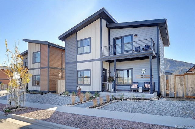 contemporary house featuring a mountain view, a balcony, and a porch