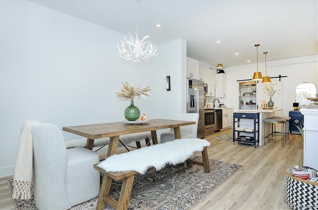 dining area with a chandelier, sink, and light wood-type flooring