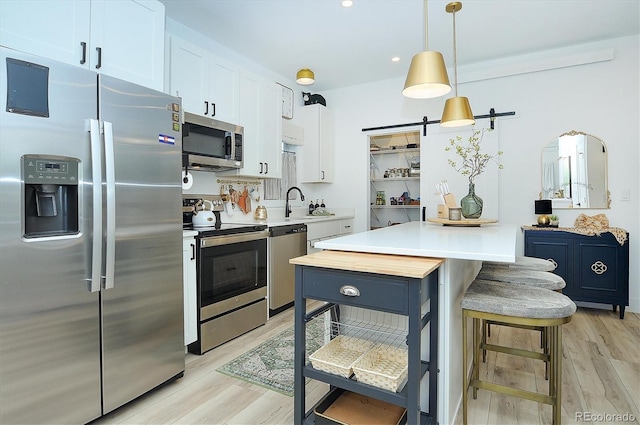 kitchen featuring pendant lighting, stainless steel appliances, a kitchen breakfast bar, and white cabinets