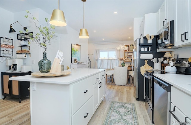 kitchen featuring appliances with stainless steel finishes, pendant lighting, white cabinetry, a center island, and light hardwood / wood-style flooring