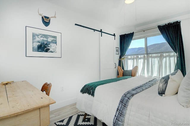 bedroom featuring a barn door, a mountain view, access to exterior, and light wood-type flooring