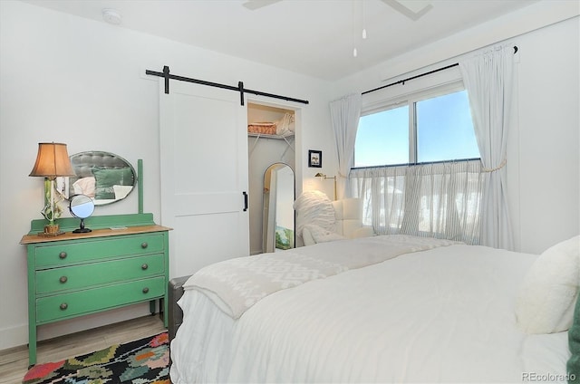 bedroom with a closet, a barn door, a spacious closet, and light wood-type flooring