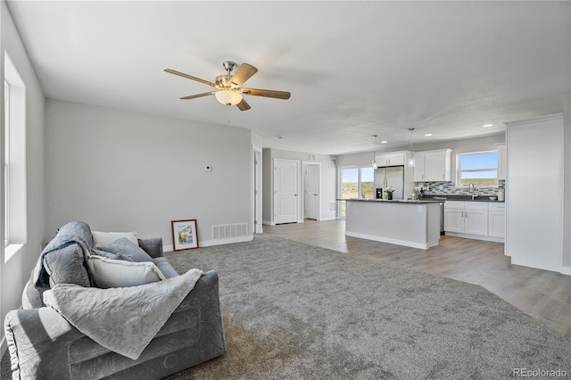 living room featuring hardwood / wood-style floors, ceiling fan, and sink