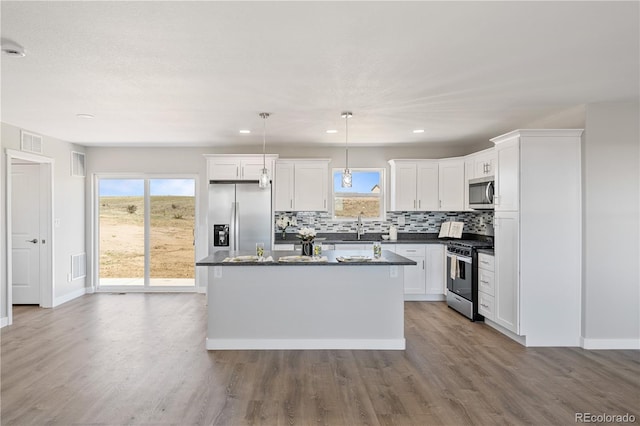 kitchen featuring a kitchen island, backsplash, stainless steel appliances, hardwood / wood-style flooring, and pendant lighting