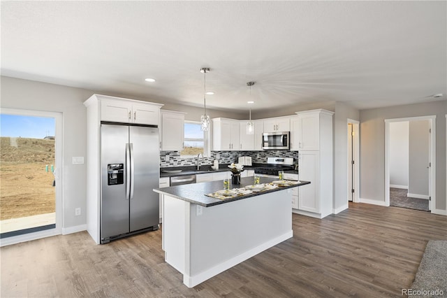 kitchen featuring appliances with stainless steel finishes, hardwood / wood-style floors, tasteful backsplash, and white cabinetry